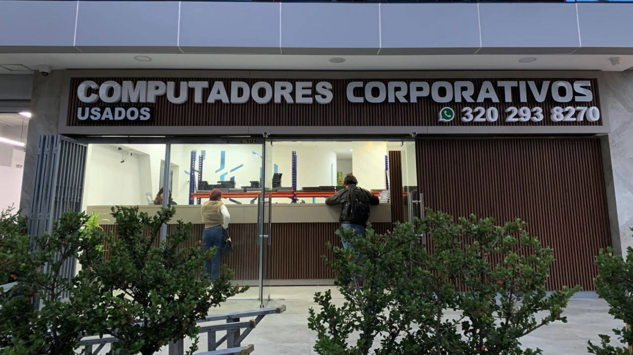 Fachada del punto de venta en Bogotá: rótulo Computadores corporativos usados, vitrina a la calle y acceso al local LC101 / 102.